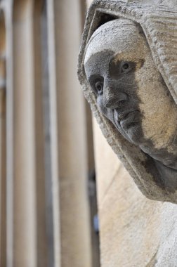 Close-up of decorative stone head carving on wall of Bodleian library courtyard, Oxford, United Kingdom. Selective focus.