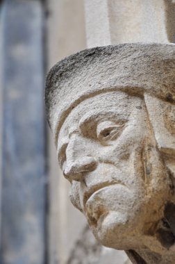 Close-up of decorative stone head carving on wall of Bodleian library courtyard, Oxford, United Kingdom. Selective focus.