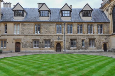 View of english lawn and building facade from Trinity College Durham Quad, Oxford, United Kingdom. Overcast Sky.
