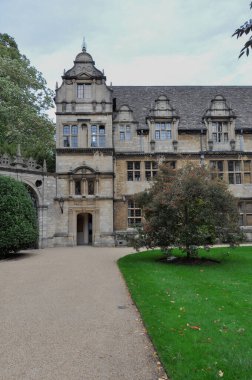 View of building facade, trees & lawn from Trinity College Front Quad, Oxford, United Kingdom. Overcast Sky.