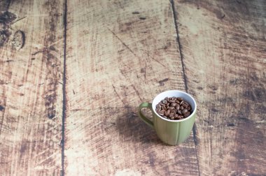 Ahşap bir fincanda yeşil fincanda kahve çekirdekleri.