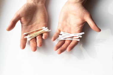 Tahta ve plastik pamuklu iki el. Plastik ve doğal maddelerin yan yana konması. Sıfır atık