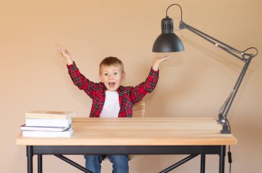 Şirin küçük çocuk masada oturuyor. Sevinçten havalara uçar ve ellerini kaldırır. Okul konseptine dönelim.