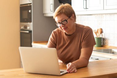 Yaşlı bir kadın dizüstü bilgisayarda çalışıyor. Modern teknolojiler ve yaşlı insanlar kavramı