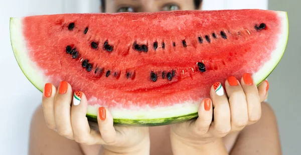 A large piece of watermelon in female hands. Manicure with nail design with a watermelon pattern. Vacation concept — Stock Photo, Image