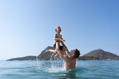 Baba ve oğul denizde oynuyorlar. Baba oğlunu fırlatır.. 