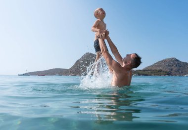 Baba ve oğul denizde oynuyorlar. Baba oğlunu fırlatır.. 