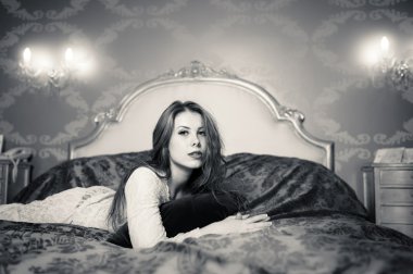 Siyah ve beyaz lüks yatakta yatan rahatlatıcı güzel genç bayan portresi