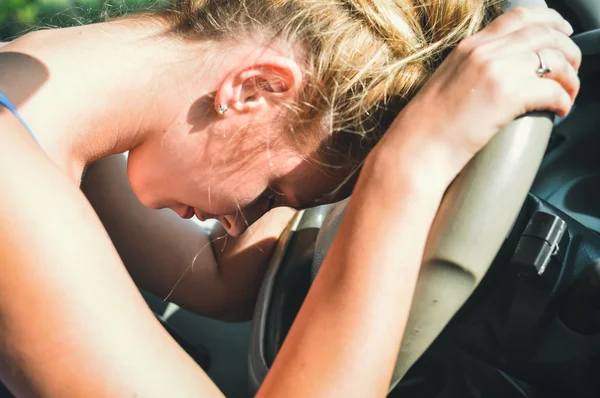 Closeup on sad tired beautiful lady driver in car leaning on the wheel — Stock Photo, Image