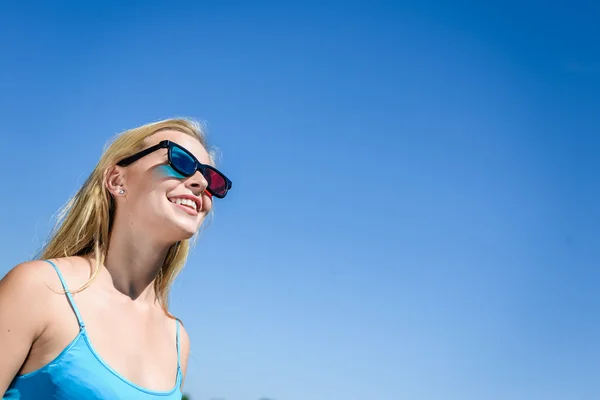 Beautiful young lady watching movie with 3D glasses, blue light background. — Stock Photo, Image