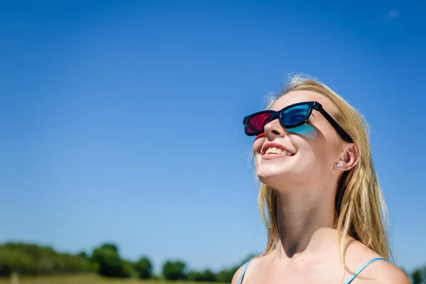 Emocionante bela jovem assistindo filme com óculos 3D, fundo azul claro . — Fotografia de Stock