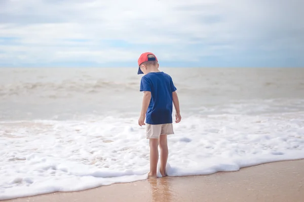 日没時に外のビーチを歩く裸足の少年のバックビュー — ストック写真