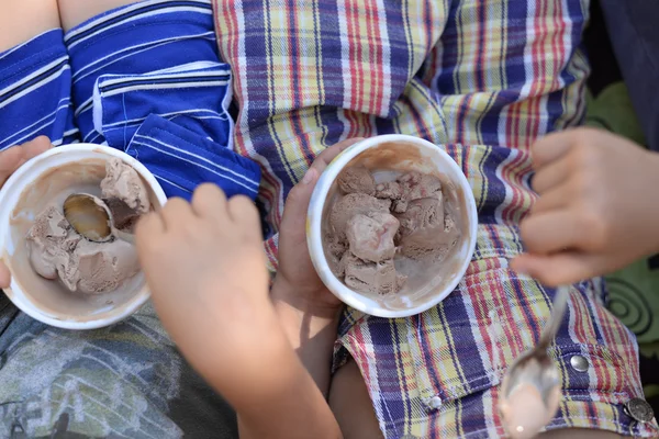 Duas crianças felizes amigos ou familiares, sentados em um banco comendo sorvete . — Fotografia de Stock