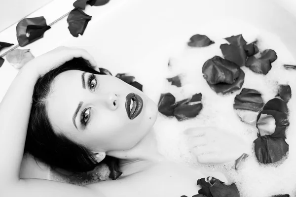 Fotografia branca preta de menina bonita sexy elegante com pele de seda se divertindo deitado em banho de água relaxante — Fotografia de Stock