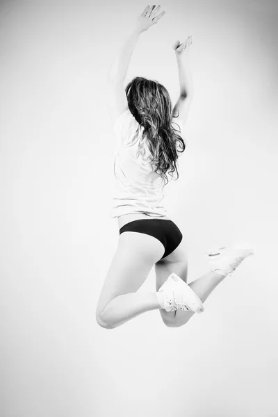 Black and white photography of beautiful young sexy lady with perfectly fit body jumping high on light background in lingerie — Stock Photo, Image