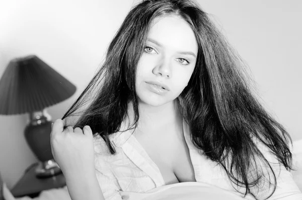 Schwarz-Weiß-Fotografie einer schönen jungen Frau mit dicken Lippen, die im Bett liegt — Stockfoto