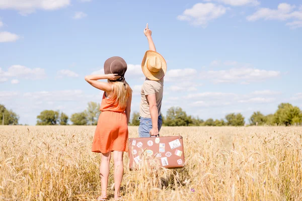 Jovem casal alegre se divertindo no campo de trigo. Homem e mulher excitados apontando para o céu azul ao ar livre — Fotografia de Stock
