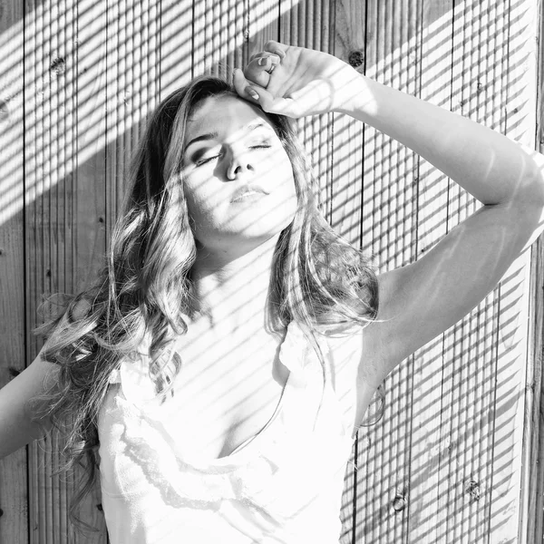 Black and white portrait of young pretty lady having fun happy relaxing over wooden background — Stockfoto