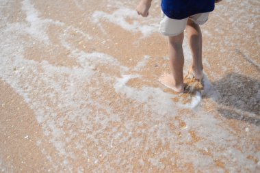 Küçük çocuk sahilde günbatımı sırasında yürüyüş closeup arkadan görünüm
