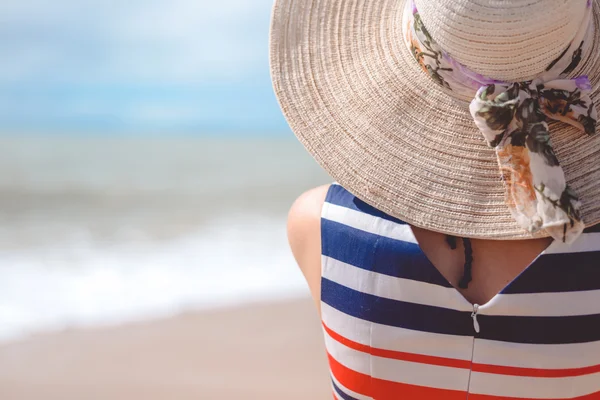 Bakifrån av elegant vacker kvinna i klänning och stråhatt på stranden. — Stockfoto