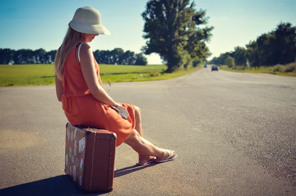 Vista posterior del lado de la joven mujer bonita autoestop esperando a lo largo de la carretera para un paseo —  Fotos de Stock