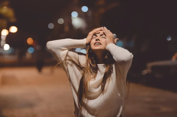 Joven mujer estresada emocional gritando mirando hacia arriba, calle de la ciudad en la noche, luces de la noche fondo bokeh al aire libre — Foto de Stock