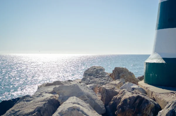 Maritime lighthouse with sunshining waters on the outside background