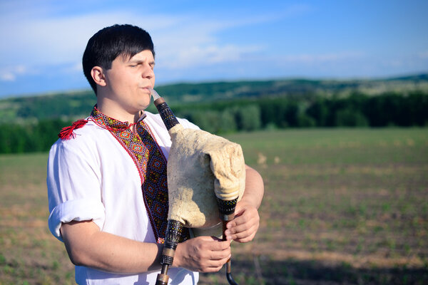 Фото молодого человека, играющего трубами на зеленом воздухе летом копировать космический фон
