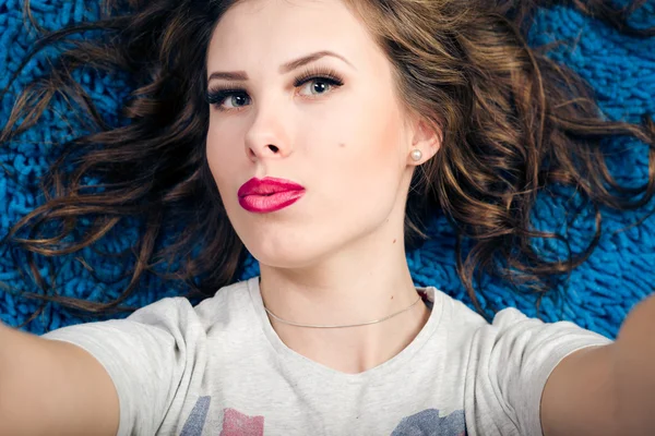 Close up portrait of making self image sexy young beautiful woman relaxing over blue carpet — Stock Photo, Image