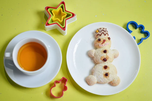 Image of snowman on white plate with colorful molds tea isolated on green background — Stock Photo, Image