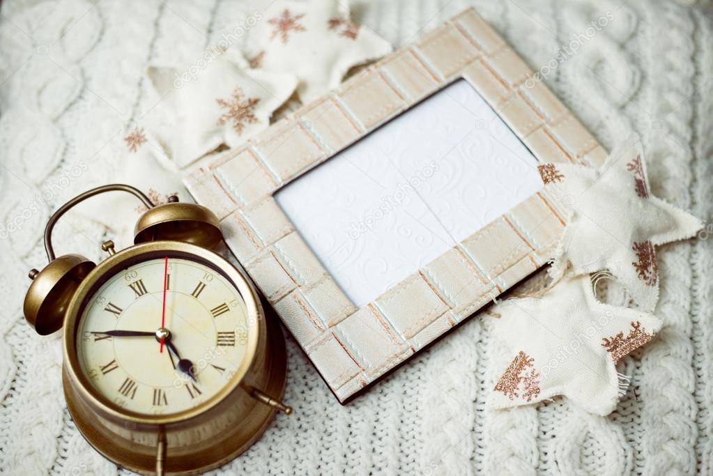 Image of alarm clock on knitted background sorounded with decorative stars