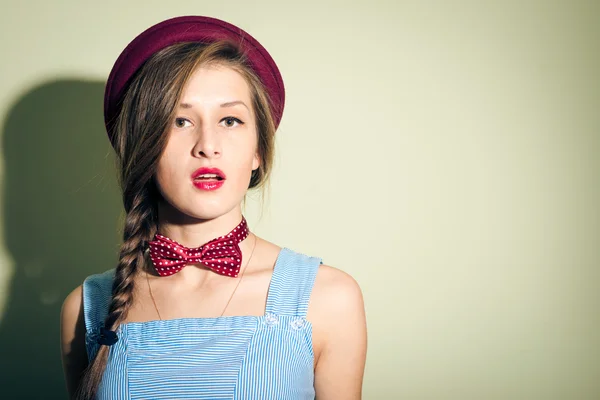 Pretty girl in red hat and bow tie looks surprised — Stock Photo, Image