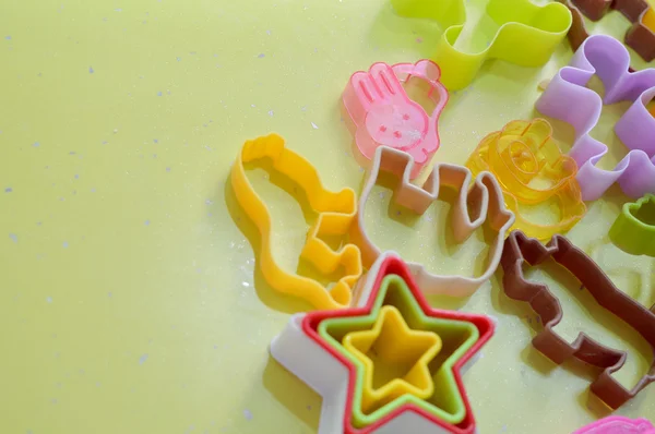 Multicolored plastic cookies cutter on green background — Stock Photo, Image