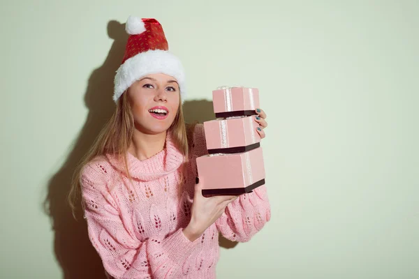Happy smiling young beautiful lady in Santa hat holding gifts boxes — Stock Photo, Image