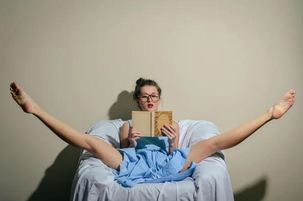 young lady wearing blue dress & glasses holding a book