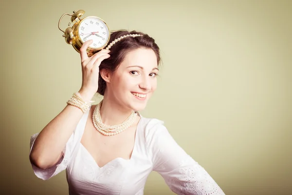 Молода леді в білій сукні весело тримає годинник на голові — стокове фото