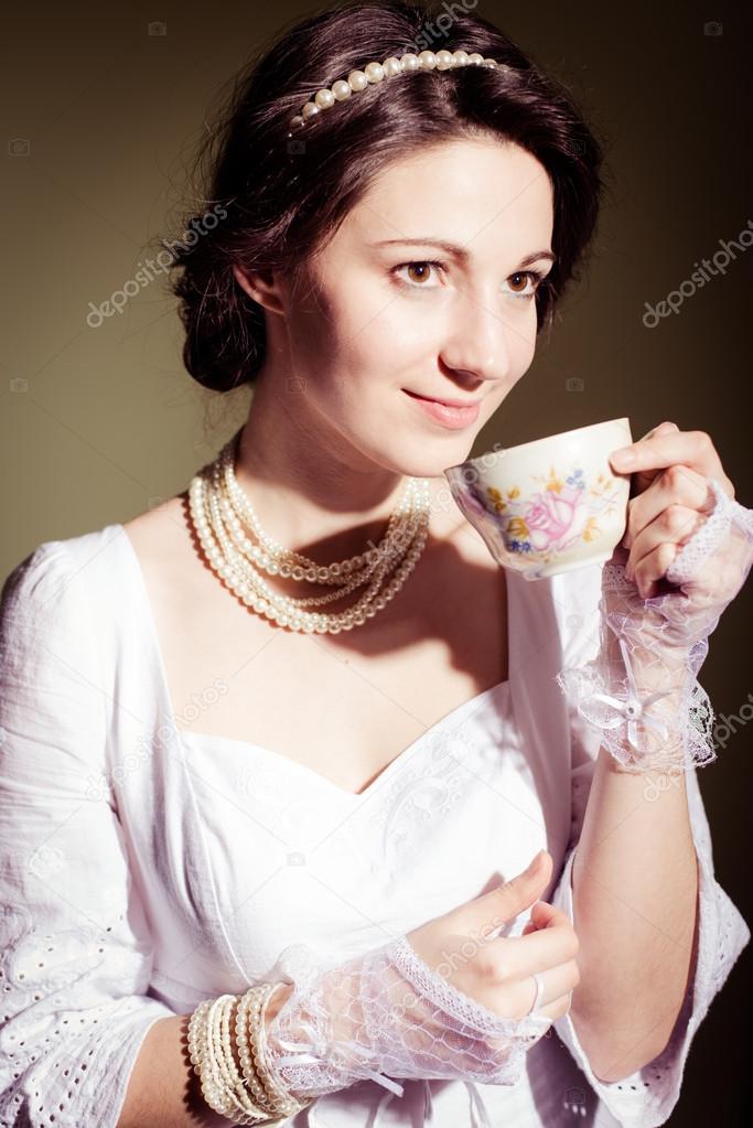 Drinking tea or coffee beautiful young lady in white dress