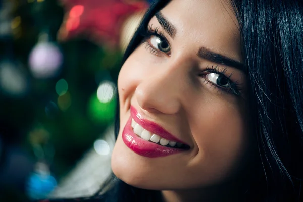 Retrato de jovem bela mulher morena feliz sorrindo e olhando para a câmera no fundo da árvore de Natal — Fotografia de Stock