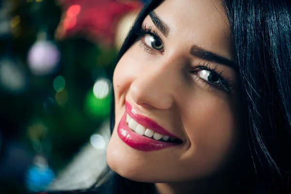 portrait of young beautiful brunette woman happy smiling & looking at camera on Christmas tree background