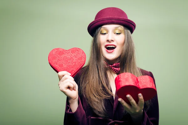 Young lady opening red present box in the form of heart