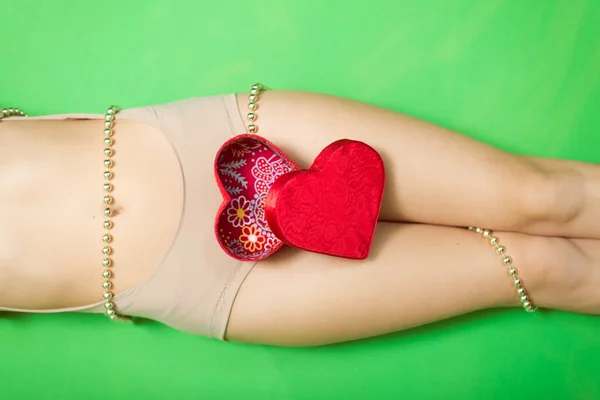 Red present gift box in the form of heart lying on beautiful sexy female legs — Stock Photo, Image