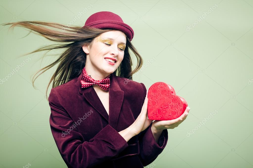 Portrait of romantic beautiful girl with red present box in the form of heart
