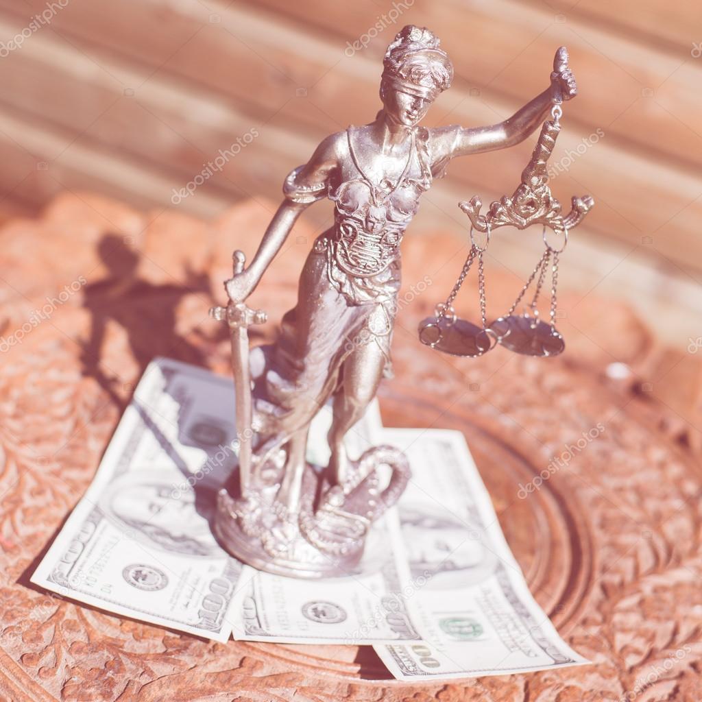money and justice: sculpture of themis, femida or justice goddess standing on money bribe symbol of corruption