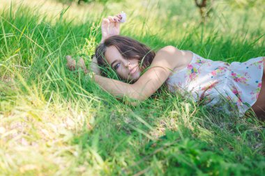 Young woman lying on soft  fresh spring grass daydreaming