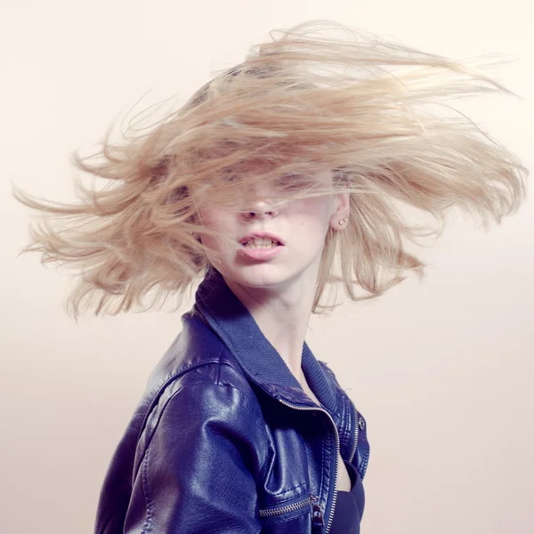 Portrait of sexy blonde girl in black leather jacket having fun moving her hair in blow — Stockfoto