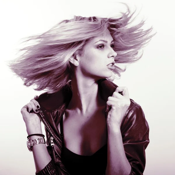 Portrait of beautiful sexi blonde girl in black leather jacket having fun in movement over light background — Stockfoto