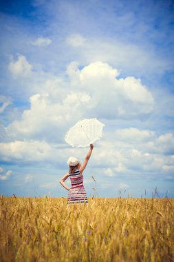 Elegant young lady in candy striped dress with white parasol in field