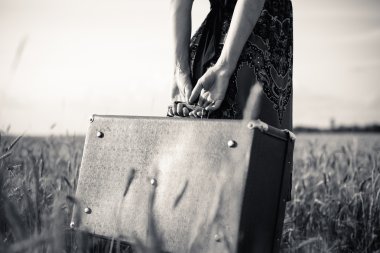 Black and white picture of slim females arms  holding retro suitcase