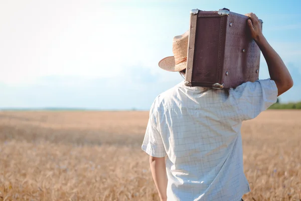 Homem de chapéu de palha com uma mala retro no ombro — Fotografia de Stock