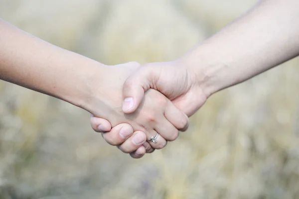 Male and female holding hands outdoors over bokeh background — 图库照片